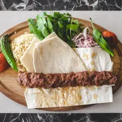 Pyszny kebab na szpadzie z ryżem, pieczonymi warzywami, świeżymi ziołami i cienkim pieczywem.