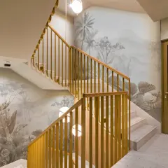 Habillage mur cage d'escalier avec un décor tropical en camaïeu. Escalier en marbre et rambarde en bois doré.