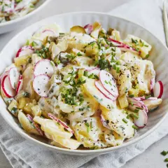 Kartoffelsalat mit Joghurt, Radieschen und Schnittlauch, garniert mit Pfeffer. Ein leichter und frischer Genuss.
