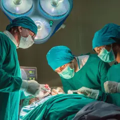 Chirurdzy w zielonych fartuchach i maseczkach skupieni na pacjencie. Zastanawiasz się, ile zarabia chirurg? To ciężka praca.