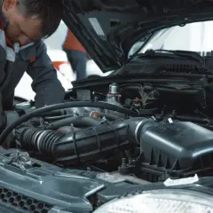 Mechanik pracuje przy silniku, sprawdzając, ile kosztuje wymiana oleju i filtrów w aucie.