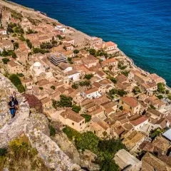 Malownicze miasteczko na skale, wspaniałe peloponez atrakcje. Dwie osoby podziwiają widok na morze i zabytkową architekturę.