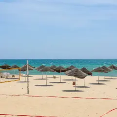 Piękna plaża w Tunezji we wrześniu. Słoneczna pogoda, turkusowe morze i rzędy parasoli zapraszają do relaksu.