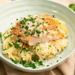 En krämig pasta alfredo kyckling, toppad med färsk persilja och riven parmesan. En utsökt måltid!