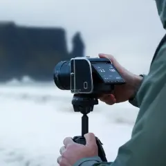 Fotograf trzyma aparat Hasselblad 907X na statywie, gotowy do uchwycenia surowego krajobrazu wybrzeża.