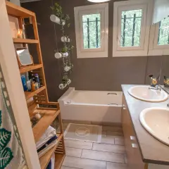 Salle de bain moderne avec baignoire, double vasque et étagères en bambou. Une idée pour relooker meuble salle de bain avec des plantes suspendues.