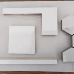 White wall tiles, including square, L-shaped, and hexagonal pieces, are laid out on a light surface, hinting at how to cut wall tile for a project.