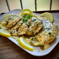 Delicioso pollo al limón con puré de patatas, adornado con rodajas de limón y perejil fresco.