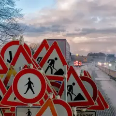 Mnóstwo znaków drogowych "roboty drogowe" i "piesi" wzywa do szczególna ostrożność na mokrej drodze.