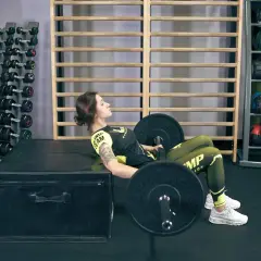 Kobieta wykonuje hip thrust, ćwiczenie angażujące mięśnie pośladków i ud.