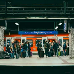Ludzie z bagażami czekają na pociąg na stacji Frankfurt am Main Flughafen Regionalbahnhof.