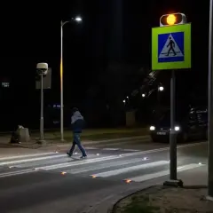 Nocą pieszy przechodzi przez pasy, oświetlone odblaskami. Obok miga żółte światło sygnalizatora, a znak d6 przypomina o obowiązku ustąpienia pierwszeństwa.