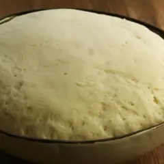 Wyrośnięte ciasto na pizzę w misce, gotowe do dalszej obróbki. Tak wygląda idealne ciasto, gdy wiesz, jak zrobić ciasto na pizzę.
