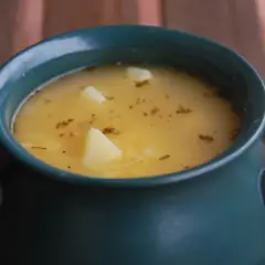 Aksamitna zupa grochowa, przepis babci, w ciemnozielonej wazie z ziemniakami i ziołami.