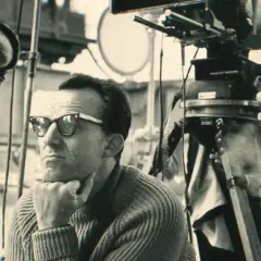 Reżyser "Zezowatego szczęścia" w okularach, zamyślony, na planie filmowym obok kamery.