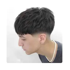 Joven con corte de pelo moderno, con flequillo recto y un degradado bajo (low fade) en los laterales.