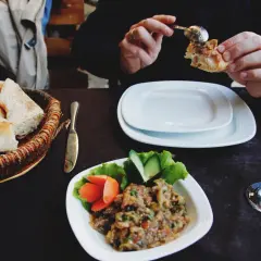 Tradycyjna kuchnia azerska: świeży chleb, sałatka z bakłażana i warzyw, talerze i kieliszki z napojami.