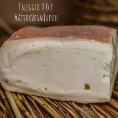 Un trozo de queso Taleggio D.O.P. con corteza rosada y pasta blanca, sobre paja. El queso Taleggio es fuerte y delicioso.