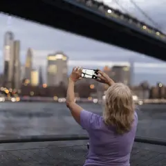 Kobieta robi zdjęcie telefonem, uchwyciła panoramę miasta w kadrze. Różne rodzaje kadrów w fotografii pozwalają na kreatywne ujęcia.
