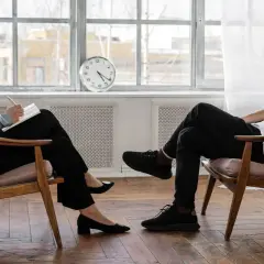 Kobieta i mężczyzna siedzą naprzeciwko siebie, prowadząc rozmowę. Klaryfikacja psychologia w trakcie sesji terapeutycznej.