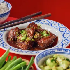 Köttgryta med fem kryddor, garnerad med salladslök, serveras med ris och gurksallad.
