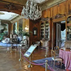 Eleganckie wnętrza Zamku w Pszczynie: kryształowe żyrandole, bogato zdobione boazerie, zabytkowe meble i biblioteka.