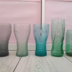 Pięć szklanek Coca-Cola w różnych kolorach. Zastanawiasz się, ile ml ma szklanka Coca Cola z Mc?
