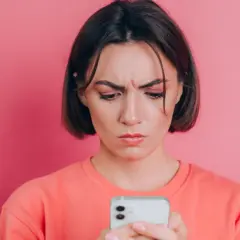Zmarszczona kobieta patrzy na telefon, zastanawiając się, jak poprawić jakość zdjęć na Instagramie.