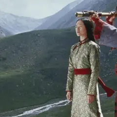 Para w tradycyjnych strojach, w tle górzysty krajobraz. Scena z kina azjatyckiego, gdzie mężczyzna przez lunetę obserwuje horyzont.
