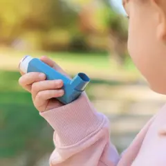 Bambina con inalatore blu, per gestire la tosse asmatica e i suoi sintomi.