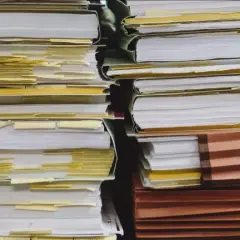 Piles of documents, some with yellow tabs, suggest a complex administrative process, perhaps a demande de relevé de carrière par courrier.