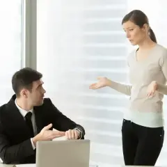 Mężczyzna w garniturze pokazuje zegarek, kobieta gestykuluje. Dyskusja o wezwaniu do sądu a praca.