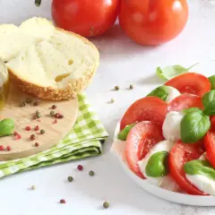 Un'incredibile insalata caprese, con pomodori freschi, mozzarella e basilico, pronta per essere condita con olio d'oliva.