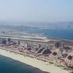 Vue aérienne d'une station balnéaire en construction en Corée du Nord, avec des bâtiments modernes, une plage et un aéroport.