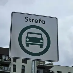 Znak drogowy "Strefa" z zielonym symbolem samochodu w okręgu.
