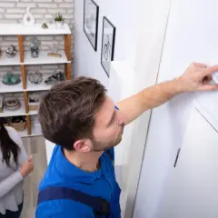 Mężczyzna montuje czujnik czadu na ścianie, kobieta obserwuje.