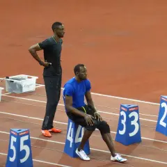 Usain Bolt, siedzący i stojący na bieżni, przypomina o jego rekordowej prędkości, która osiągnęła ponad 44 km/h.