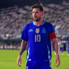 Messi w niebieskiej koszulce reprezentacji Argentyny, z numerem 10 na piersi, na tle trybun pełnych kibiców.