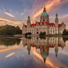Nowy Ratusz w Hanowerze, jeden z najpiękniejszych zamków w Niemczech, odbija się w spokojnej tafli jeziora o zachodzie słońca.