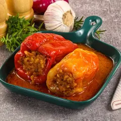 Pyszne papryki faszerowane bez mięsa, w sosie, obok czosnku i ziół.