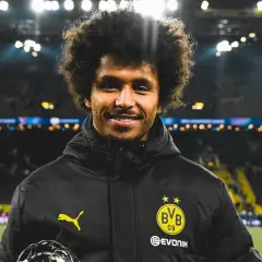 Karim Adeyemi z BVB z pucharem, uśmiecha się na tle stadionu.