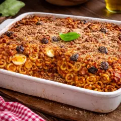 Piatto fumante di anelletti alla siciliana, con uova sode, olive nere e croccante panatura.