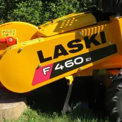Żółty frez do pni drzew LASER F460 EI z czerwonym uchwytem i tarczą tnącą, gotowy do pracy na trawie.