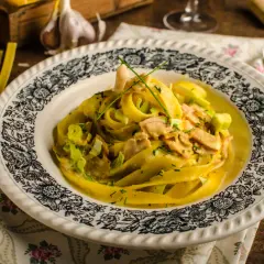 Talerz z makaronem tagliatelle w kremowym sosie z kawałkami mięsa i szczypiorkiem.