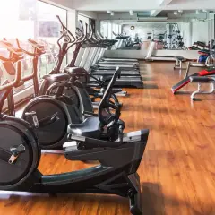 Rząd bieżni i rowerów treningowych w nowoczesnej siłowni z drewnianą podłogą.