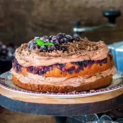 Pyszny tort porzeczkowy z kremem czekoladowym, udekorowany świeżymi porzeczkami i wiórkami czekolady.