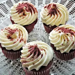 Fem röda sammetsmuffins med fluffig cream cheese frosting, strösslade med smulor.