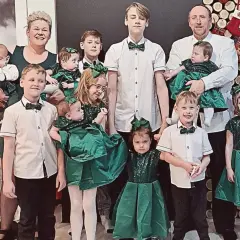 Rodzina z pięcioraczkami w zielonych strojach, pozująca do zdjęcia.