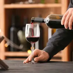 Versando vino rosso in un bicchiere, si notano i difetti del vino: torbidità e sedimenti.