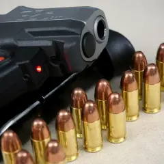 Pistolet i naboje, gotowe do akcji. To obraz, który symbolizuje produkcję broni i jej potencjalne użycie.